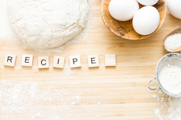 the word recipe is written in letters on the table. Flour, eggs, salt, sugar