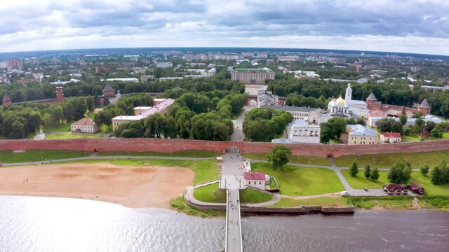 Panoramic aerial view of the Volkhov River and the old town of Veliky Novgorod, the red brick Kremlin in the rays of the setting sun and natural attractions of Russia.