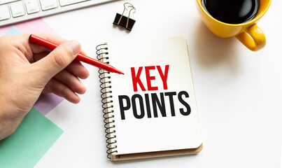 Hand with red pen. Cofee cup. Stick. Keyboard and white background. KEY POINTS sign in the notepad