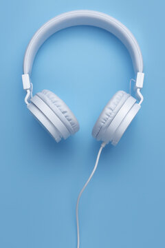 Close-up vertical image of white headphone on blue background. Music concept.