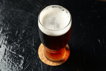 Glass of beer on black table, close up