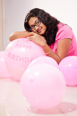 Fototapeta na wymiar portrait of an indian girl dressed in pink dress with pink balloons on her birthday with selective focus on balloon