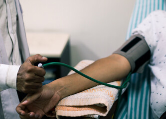 blood pressure cuff tied in arm of a patient and inflated by attendant arm