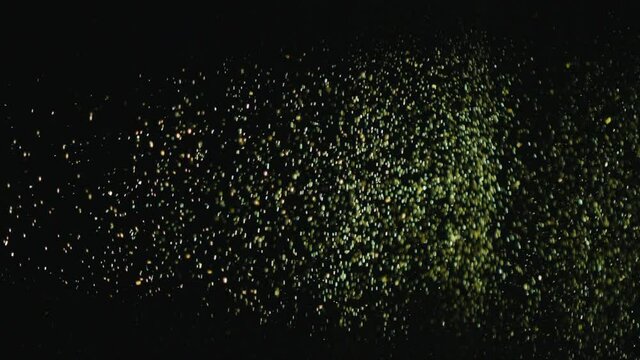 Explosion of gold sparkles falling in the form of rain on a black background