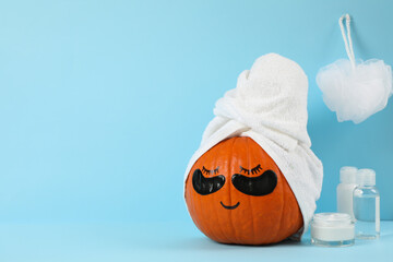 Skincare accessories and pumpkin with eye patches on blue background