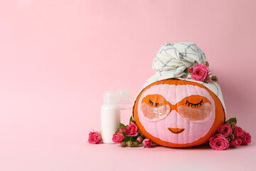 Skincare supplies, pumpkin with eye patches and towel on pink background
