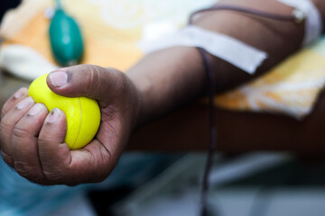 selective focus of blood collection during blood donation and ball in palm for squeezing