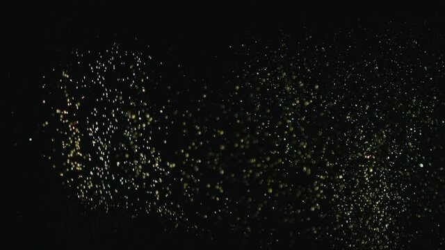 Explosion of gold sparkles falling in the form of rain on a black background