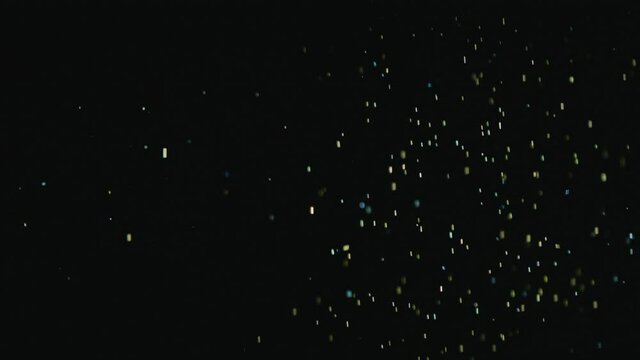 Golden sparkles fall in the form of rain on a black background
