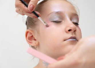 makeup artist makes a festive shining makeup for beautiful young girl. makeup for Halloween or new...