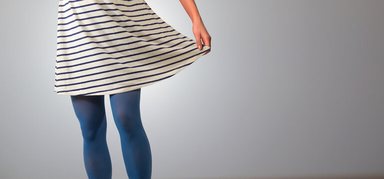 Woman legs close up in striped dress. Isolated against grey background.