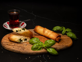 Turkish börek on plate , Famous Turkish rolls called sigara boregi, served with tomatoes,  and tea.