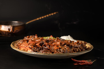 Traditional Turkish Bursa iskender kebap doner served with special red sauce and yogurt , garnished with grilled tomatoes and peppers