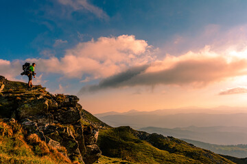 A little boy standing on a large rocky rock admires the landscape of the Carpathians, the top of Mount Pip Ivan Chornohirsky.