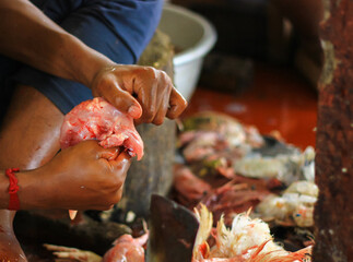 butcher cutting chicken on a standing blade dao with hand for sale