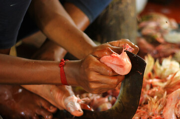 butcher cutting chicken on a standing blade dao with hand for sale