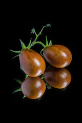 Tomatoes on a black background with reflection