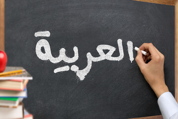 Hand writing on a blackboard in a Arabic language learning class course with the text 