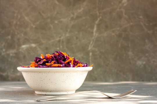 Vitamin red cabbage salad with carrot and bean sprouts in a boal on gray background. Healthy eating, vegan food concept