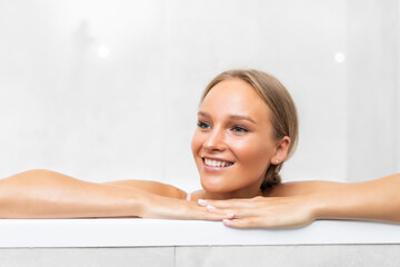 Portrait of smiling young woman laying in bathtub