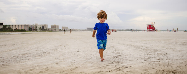 Boy playing on the beach at siesta Key florida with the snd and birds  - obrazy, fototapety, plakaty
