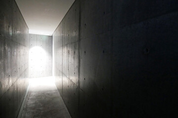 コンクリートの壁、暗い廊下と奥に照明