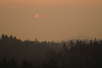 Very hazy and smokey view over Lake Tahoe near sunset, during wildfire season, with trees in the...