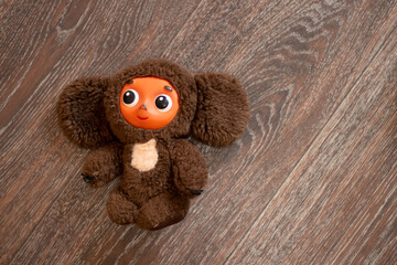 children's old toy cheburashka character from the cartoon lies on the wooden floor