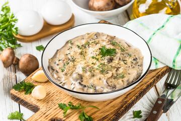 Champignons in cream sauce at white table.