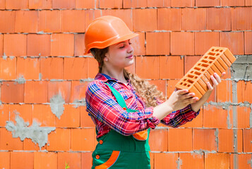 building a house. Kid build construction. engineer teen worker. Professional craftsman or workman. International workers day. girl in helmet plays builder with brick. Old brick wall repair.