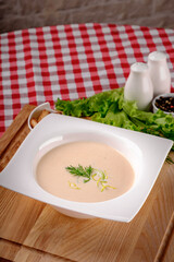 A bowl of creamy potato soup with crackers bread on white plate in italian restaurant background, top view. Vegetable cream soup. Italy food. Close up. space