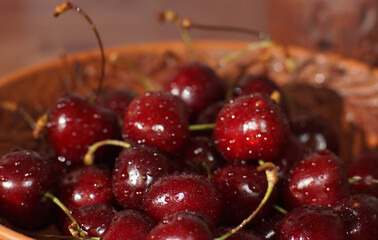 A beautiful, juicy, red cherry berry lies in a brown bowl.