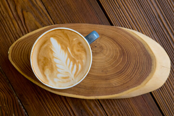 Latte coffee in a cup on a wooden table with copyspace. Top flat view.