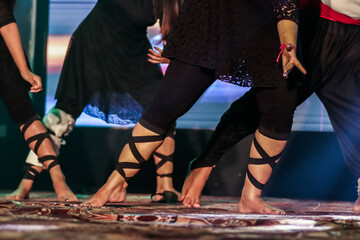 feet of a dancer on stage doing hip hop dancing stance with background neon lights