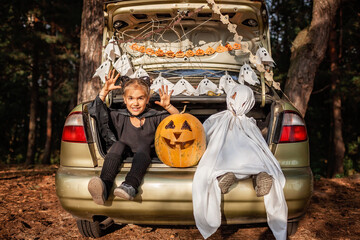Safe distant Halloween celebration. Kids preparing decoration for party in the trunk of car © Maria