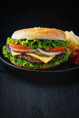 Tasty hamburger with french fries on wooden table. Copy space.