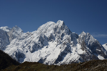 Snow covered peaks in the Himalayas, as see from a high plateau in Nepal, on a bright sunny day with vivid blue skies