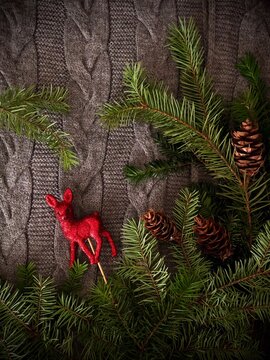 Fir Branches With Cones And Toy Deer On A Gray Jersey Background