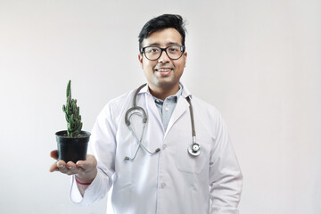 male indian doctor in white coat and stethoscope with a cactus plant on a pot