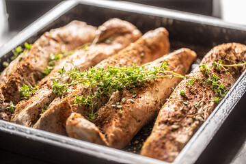 pork fillets in a baking dish seasoned with spices and herbs before baking