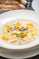 Chicken soup in a plate with noodles, carrots and fresh parsley on top