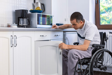 Young man sitting on wheelchair in kitchen