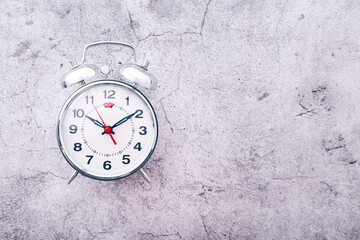 Silver alarm clock on cement background. Top view. Copy space