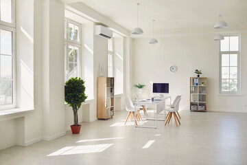 Workplace in a modern bright office with large windows, white table and chairs.