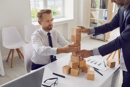 Entrepreneurs Of Different Generations Building Tower Together As Metaphor For Business Succession