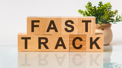 FAST TRACK motivation text on wooden blocks business concept white background. Front view concepts, flower in the background