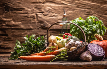 Selection of autumn fresh harvest of vegetables on a vintage wooden surface and inside a basket