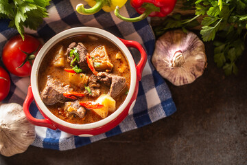 Top views of bowl of goulash soup with meat, potatoes and chillies
