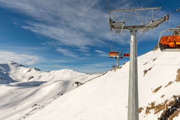 Scenic panoramic view of alpine peaks with ski lift ropeway on hilghland mountain winter resort and...