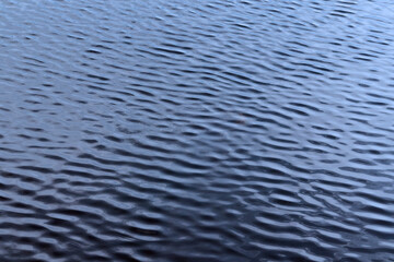 Small ripples on a blue water. Close-up view of the wavelets. Abstract natural texture or background